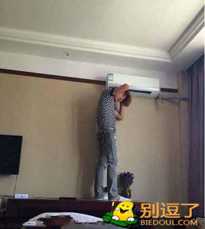 男子利用空调风吹头发 男子利用空调风吹头发